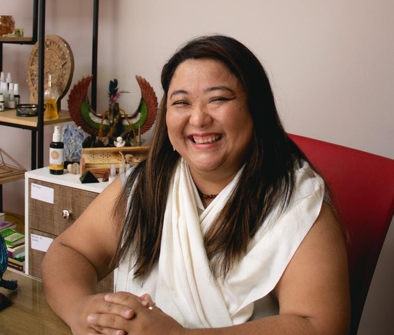 Martha Uechi sorrindo, sentada à mesa de atendimento